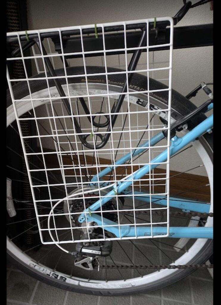 荷台にワイヤーネットを固定して、荷物がチェーンに触れないようにした自転車の後輪部分。