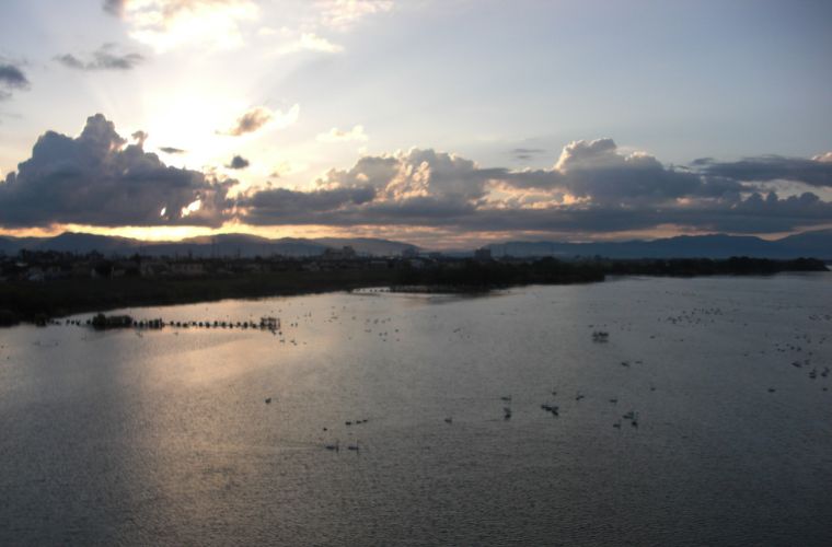 朝の光が差し込む湖と雲が広がる空。
